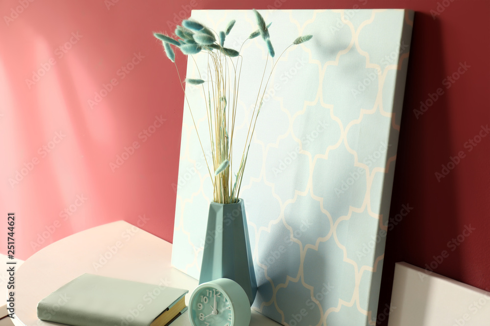 Vase with picture on table near color wall