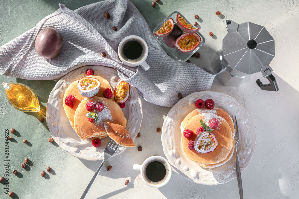 Tasty pancakes with passion fruit, berries and coffee on table