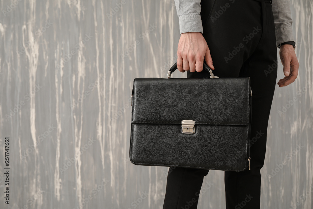 Handsome businessman with stylish briefcase on grey background