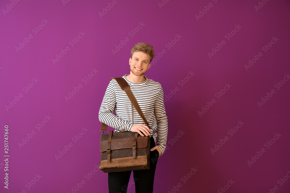 Handsome man with stylish briefcase on color background