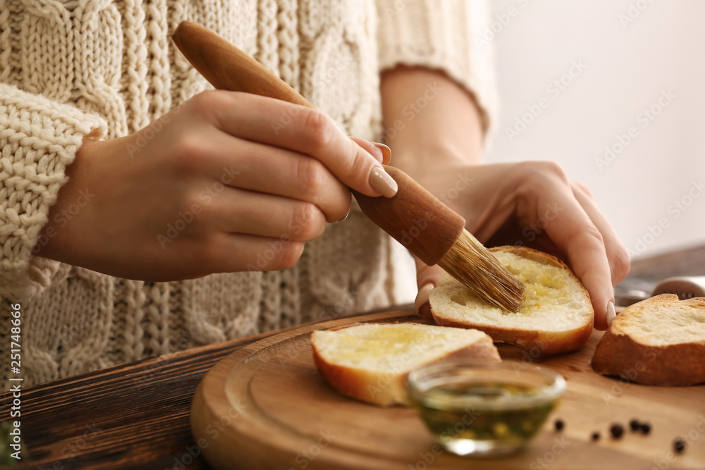 Woman making tasty garlic bread in kitchen, closeup