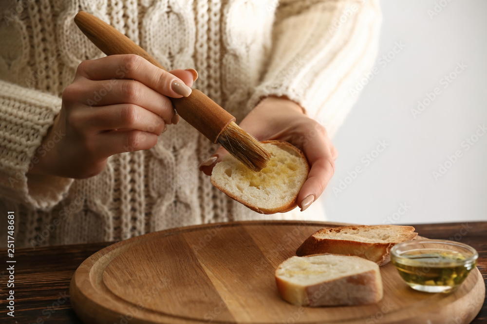 Woman making tasty garlic bread in kitchen, closeup