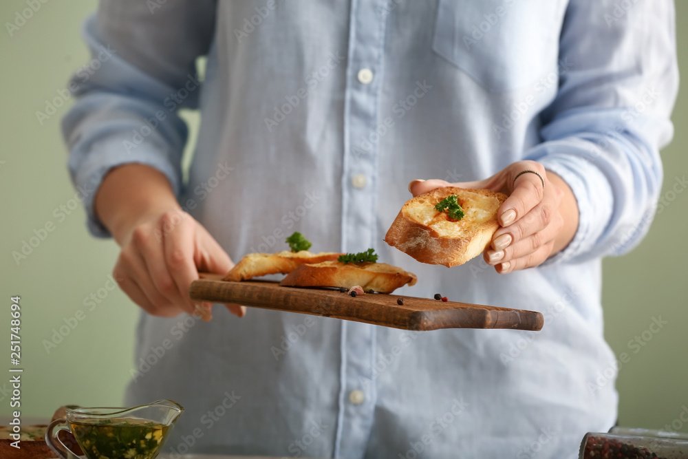 Woman holding board with tasty garlic bread, closeup