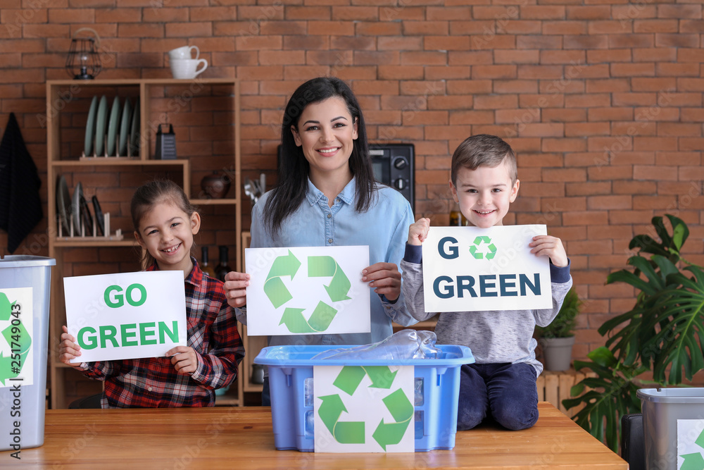 Family holding paper sheets with text GO GREEN and recycling symbol at home