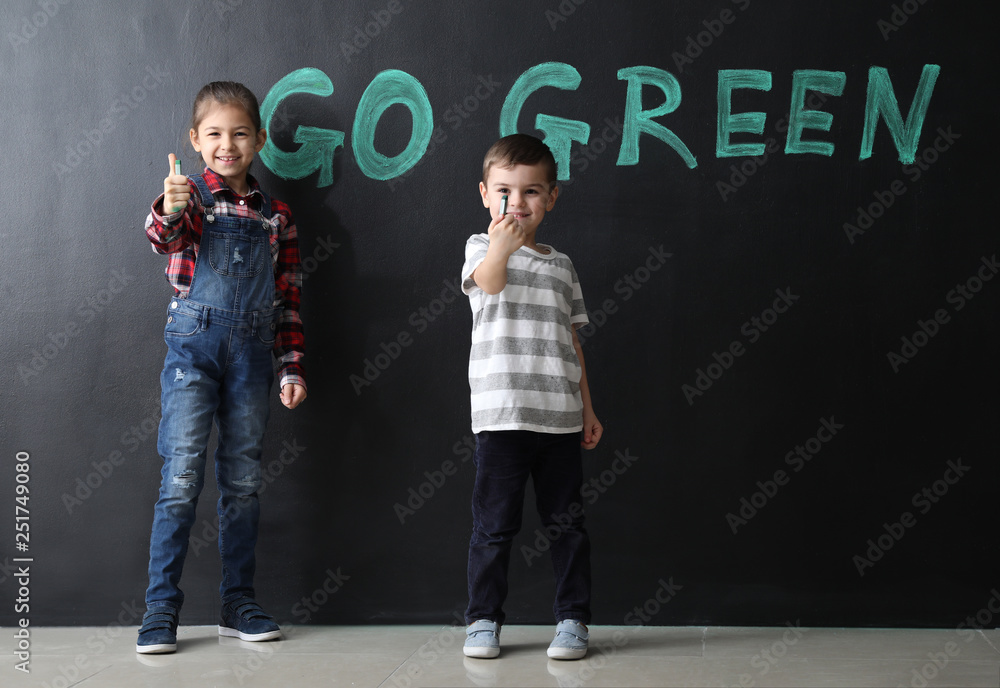 Little children near dark wall with text GO GREEN