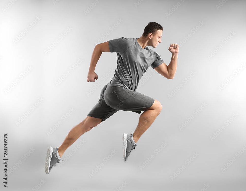 Sporty young man running against grey background