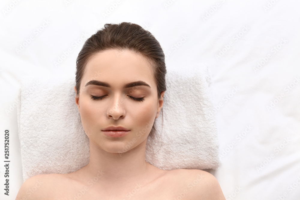 Young woman undergoing eyebrow correction procedure in beauty salon