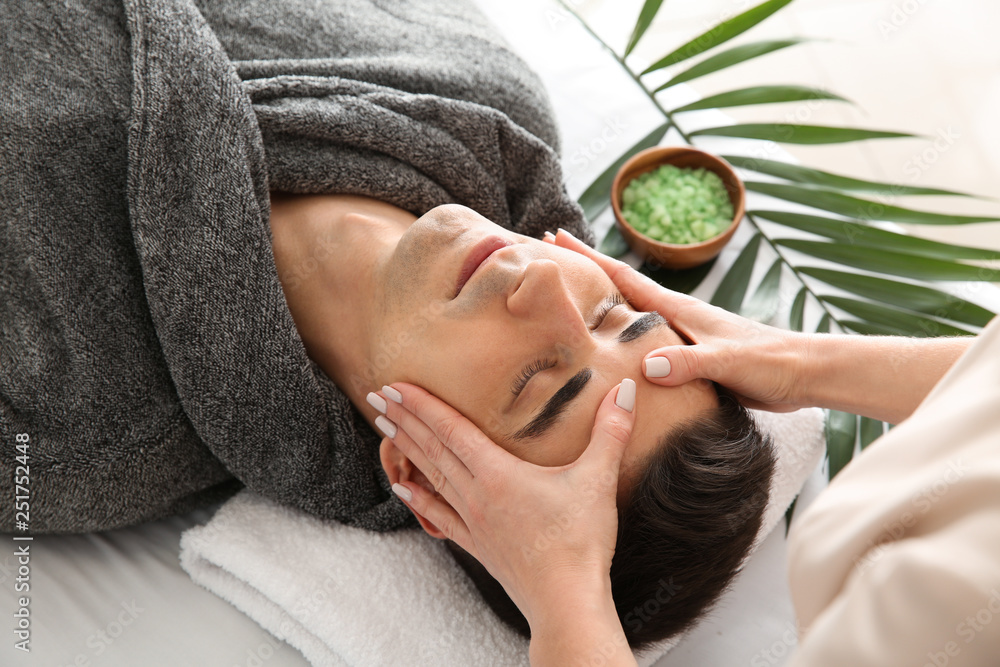 Man receiving face massage in beauty salon