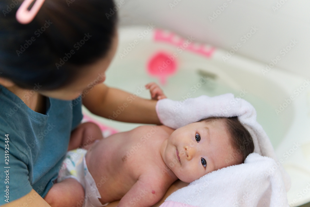 Asian mother dry her newborn baby hair with towel after rinsing shampoo from the hair in bathroom. M