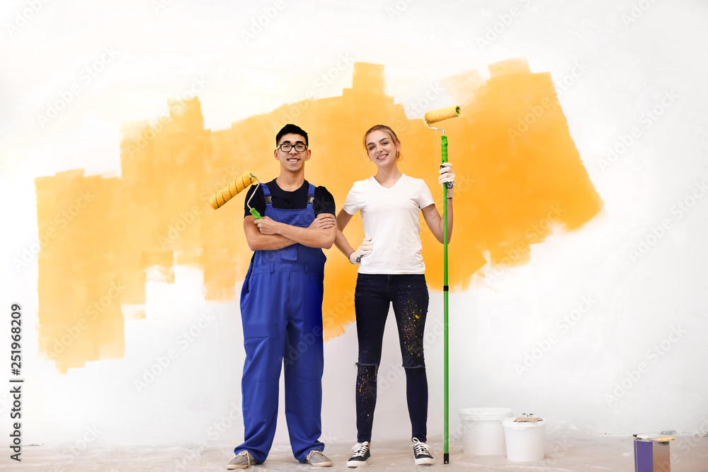 Professional decorators with paint rollers indoors