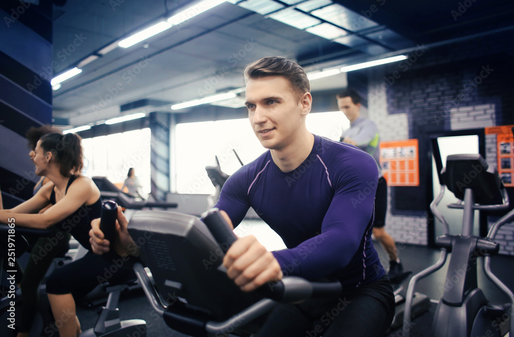 Young man training on special sport equipment in gym