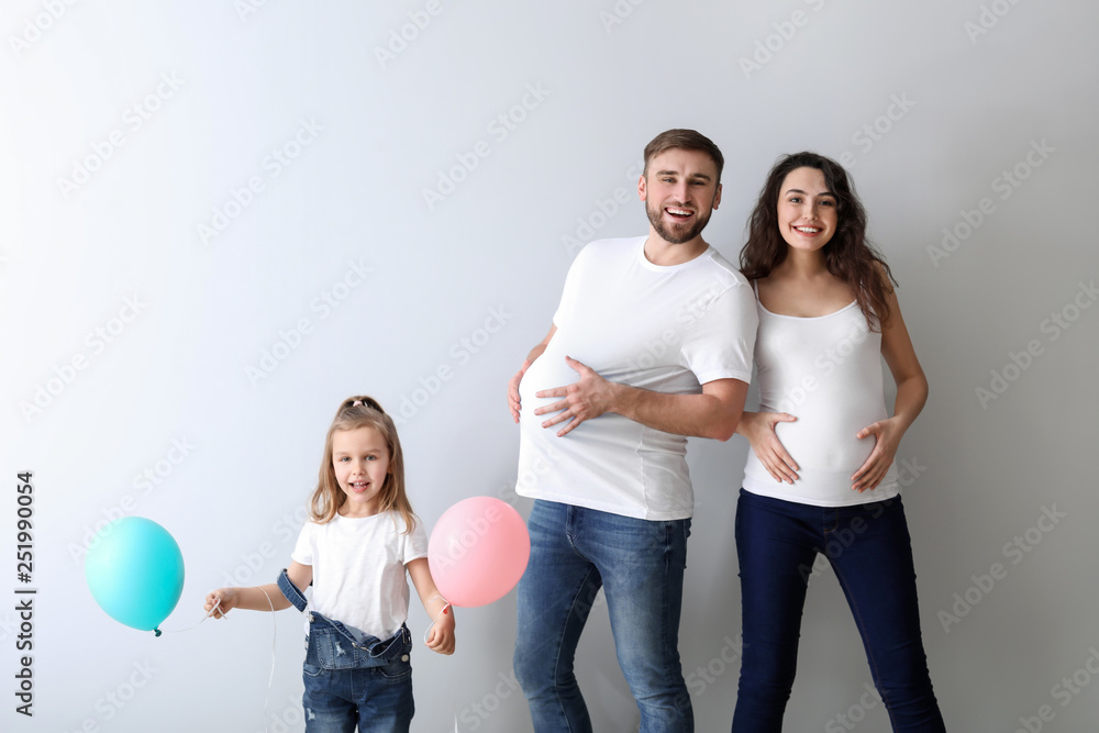 Happy family expecting baby on light background