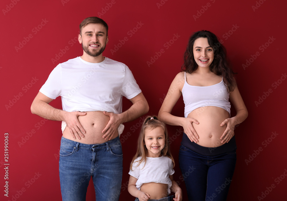 Happy family expecting baby on color background