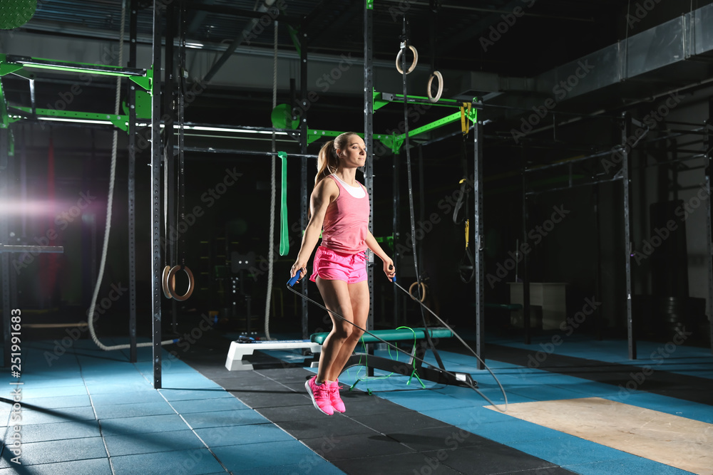 Young sporty woman jumping a rope in gym