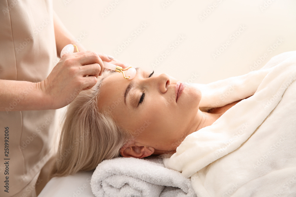 Mature woman receiving face massage in beauty salon