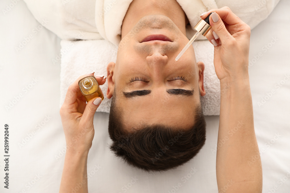 Man undergoing treatment with face serum in beauty salon