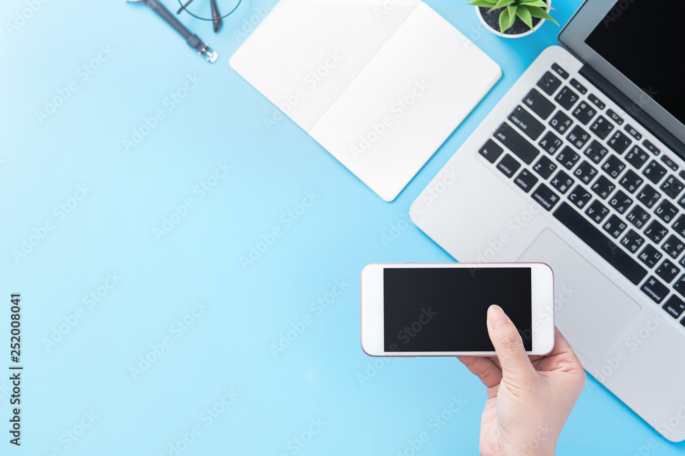 A woman is holding a smartphone isolated with a minimal blue desk, concept of online shopping paymen