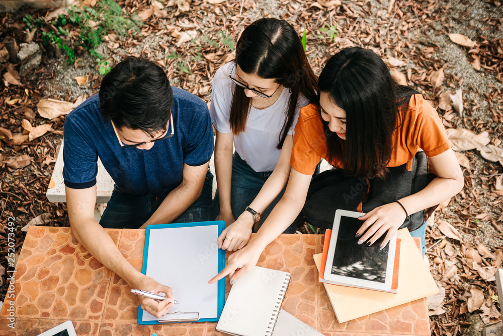 A group of young or teen Asian student in university smiling and reading the book and look at the ta