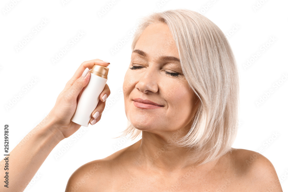 Female hand applying serum onto mature womans face against white background