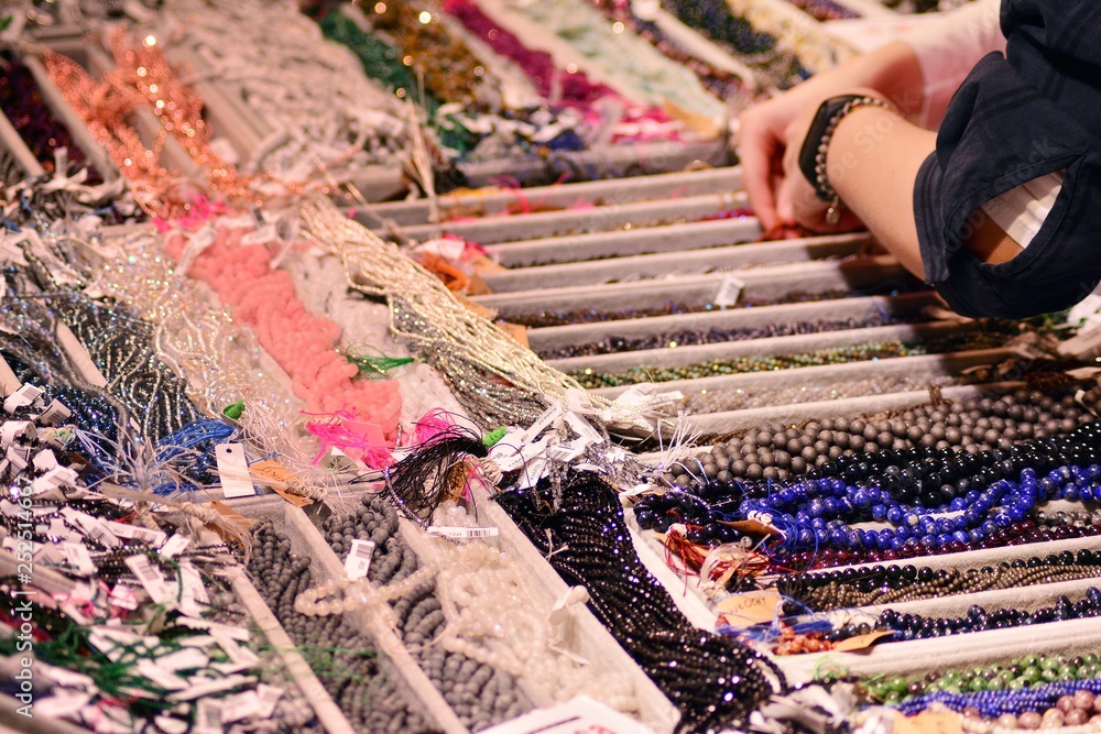 A woman chooses jewelry with precious stones in a jewelry store