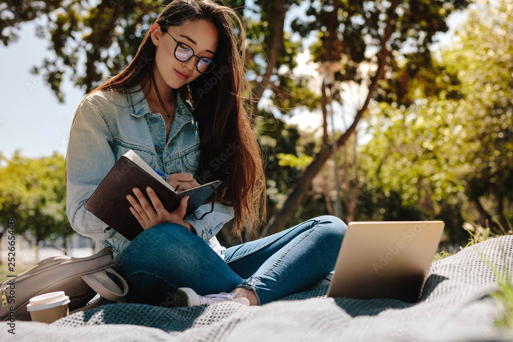 Young woman studying sitting outdoors