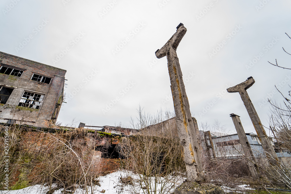 Remaining pillars of the destroyed buildings on the background of abandoned houses in winter. Ruined