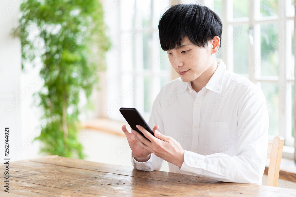 young asian man using smart phone in living room