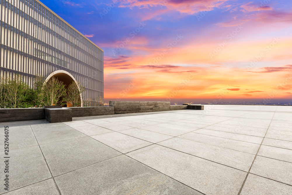 Empty square floor and modern city skyline with buildings at sunset