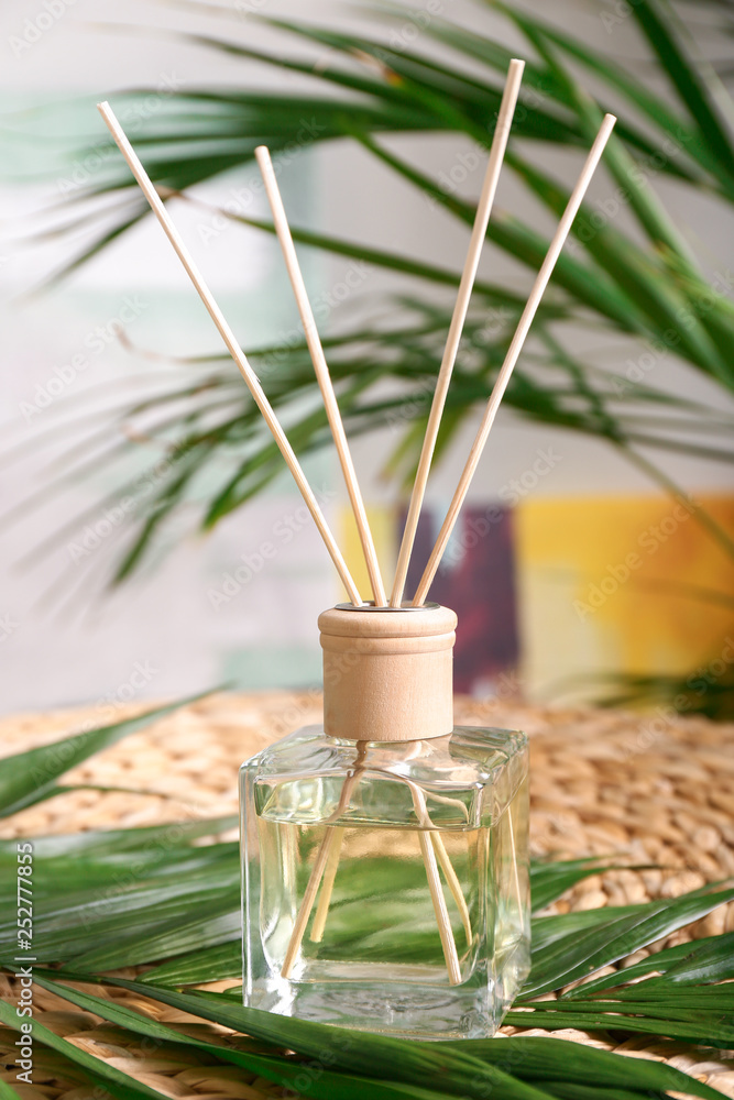 Reed diffuser and tropical leaves in room