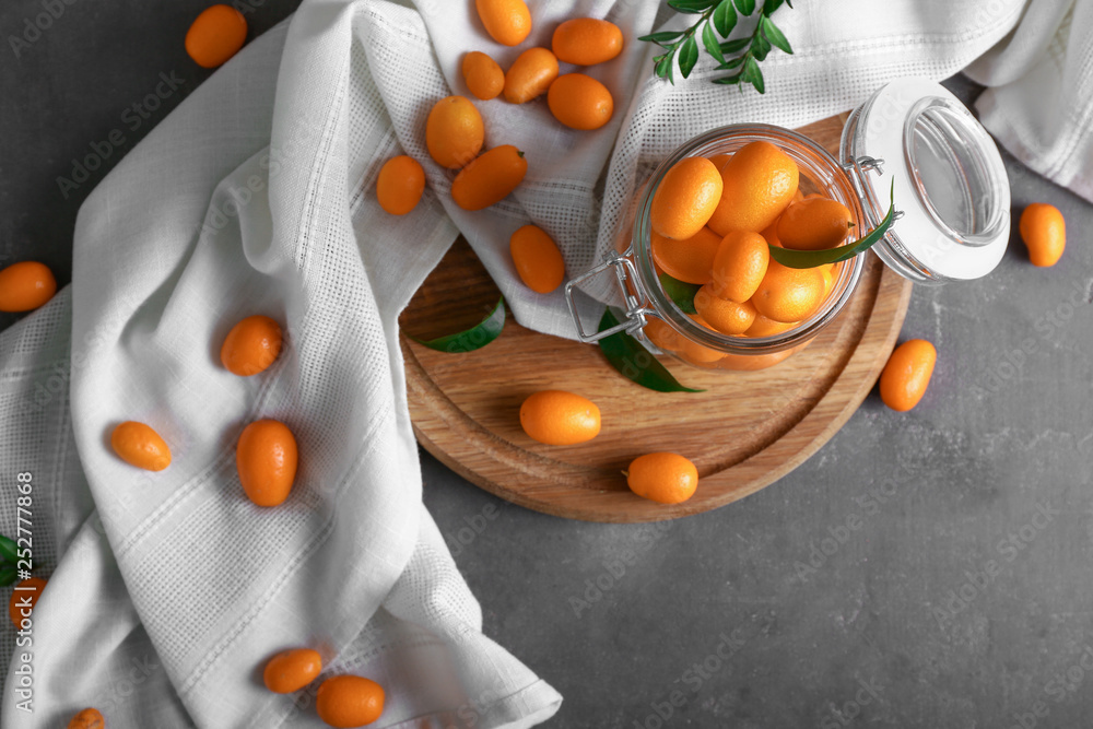 Glass jar with delicious kumquat fruit on table