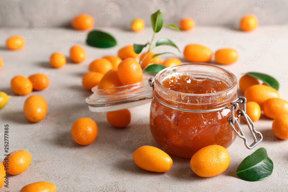 Jar with delicious kumquat jam on table