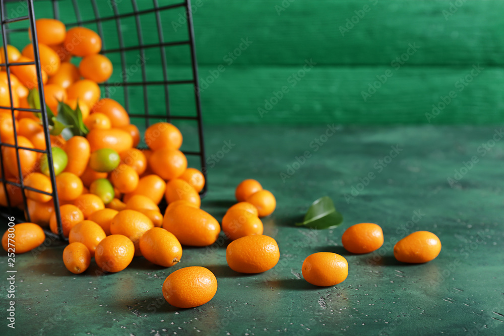 Overturned basket with delicious kumquat fruit on table