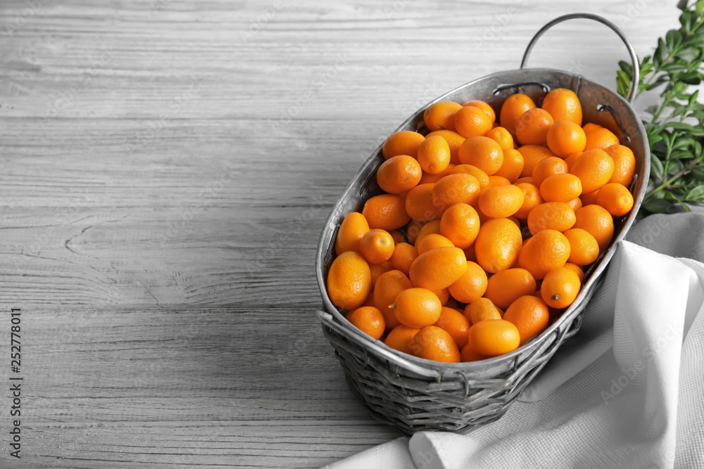 Basket with delicious kumquat fruit on table