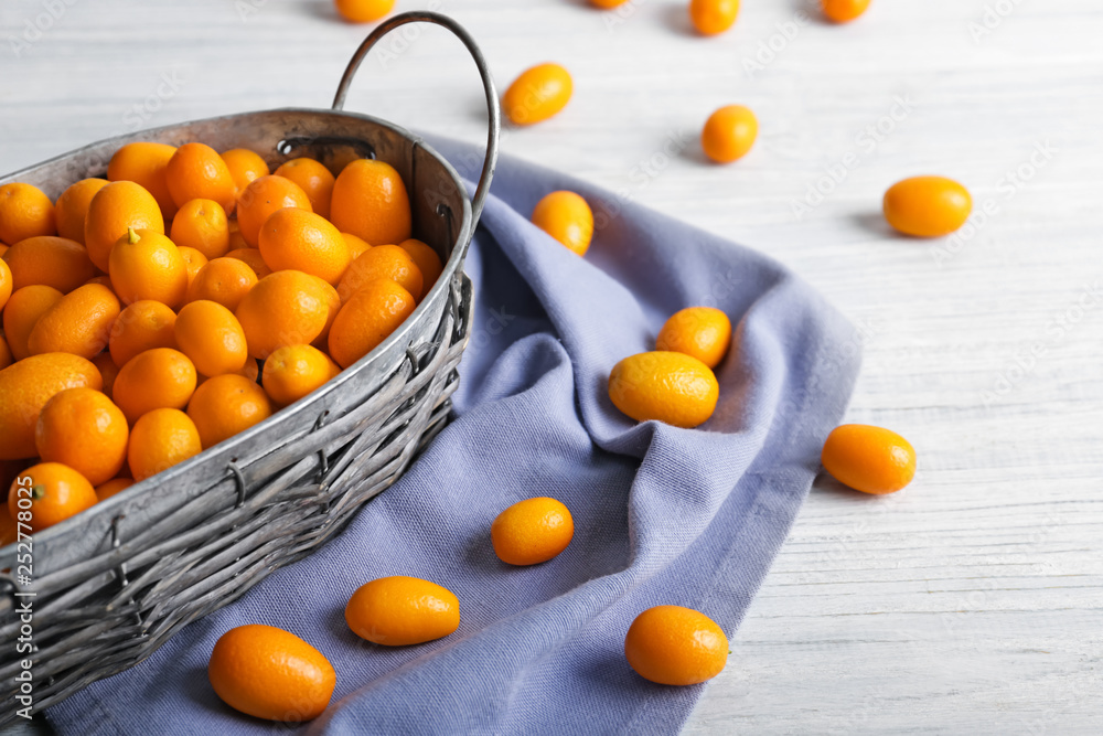 Basket with delicious kumquat fruit on table