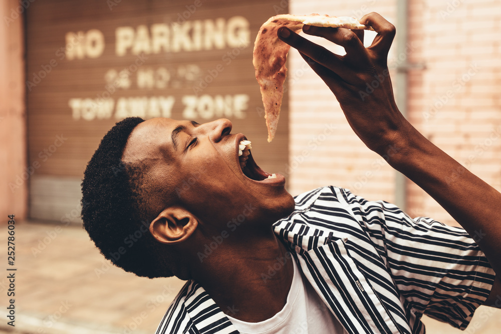 African man eating pizza