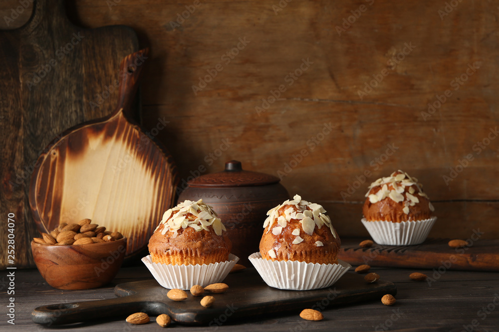 Board with tasty almond muffins on wooden table