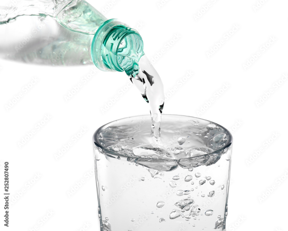 Water pouring from bottle into glass on white background