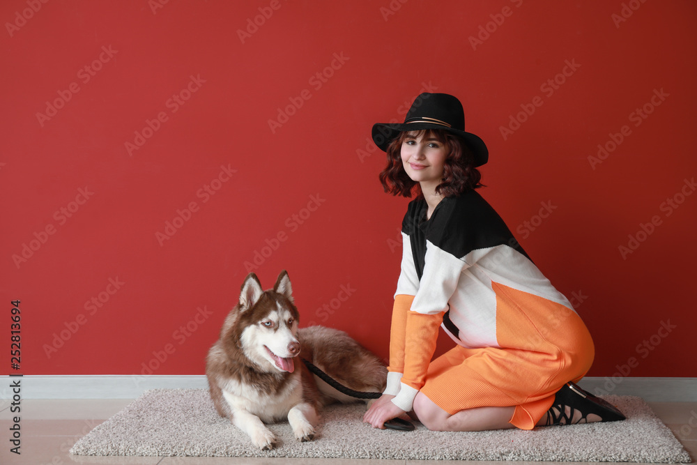 Young woman with her cute dog near color wall