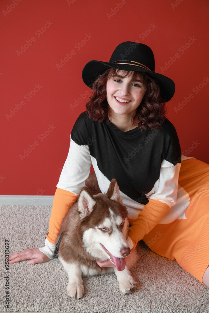 Young woman with her cute dog near color wall