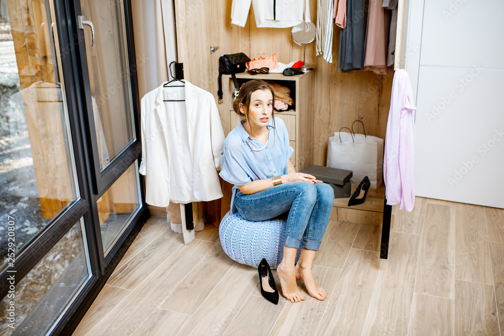 一个年轻女人坐在家里装满衣服的衣柜里的肖像