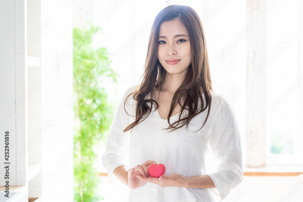 attractive asian woman holding heart symbol