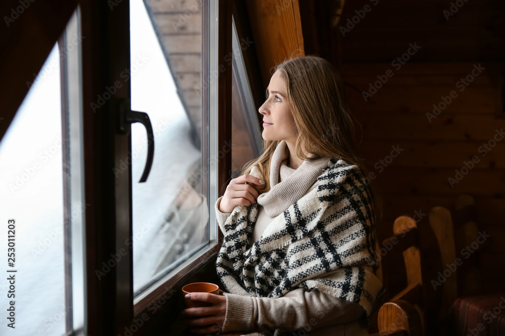 冬日在窗户附近喝热饮的年轻女子