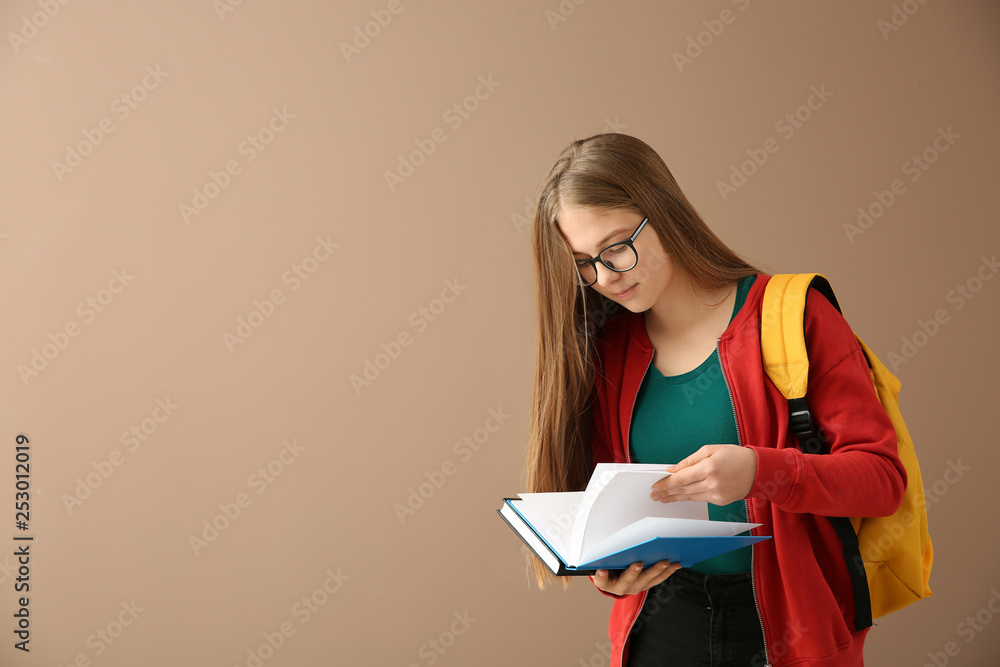 Schoolgirl with books on color background