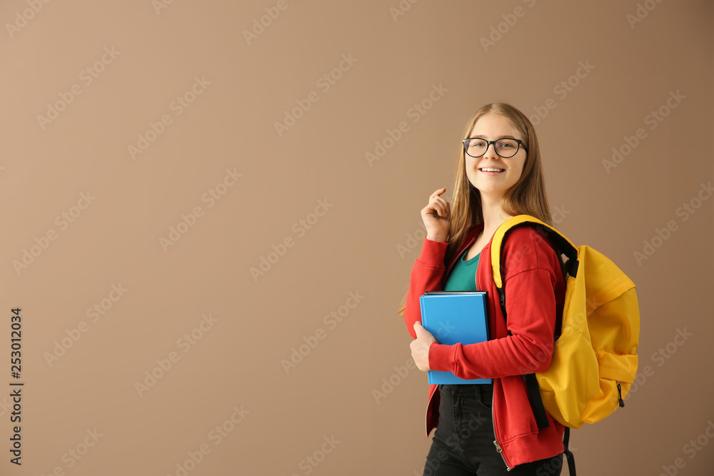 Schoolgirl with books on color background