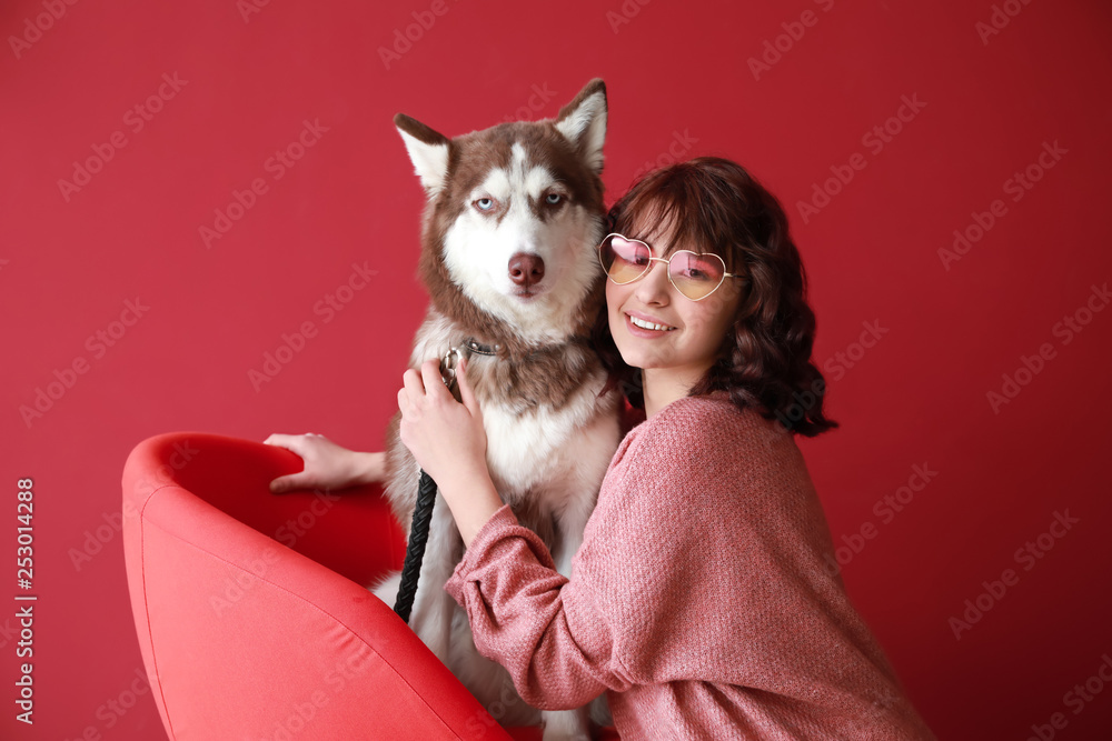 年轻的女人和她可爱的小狗在彩色背景上