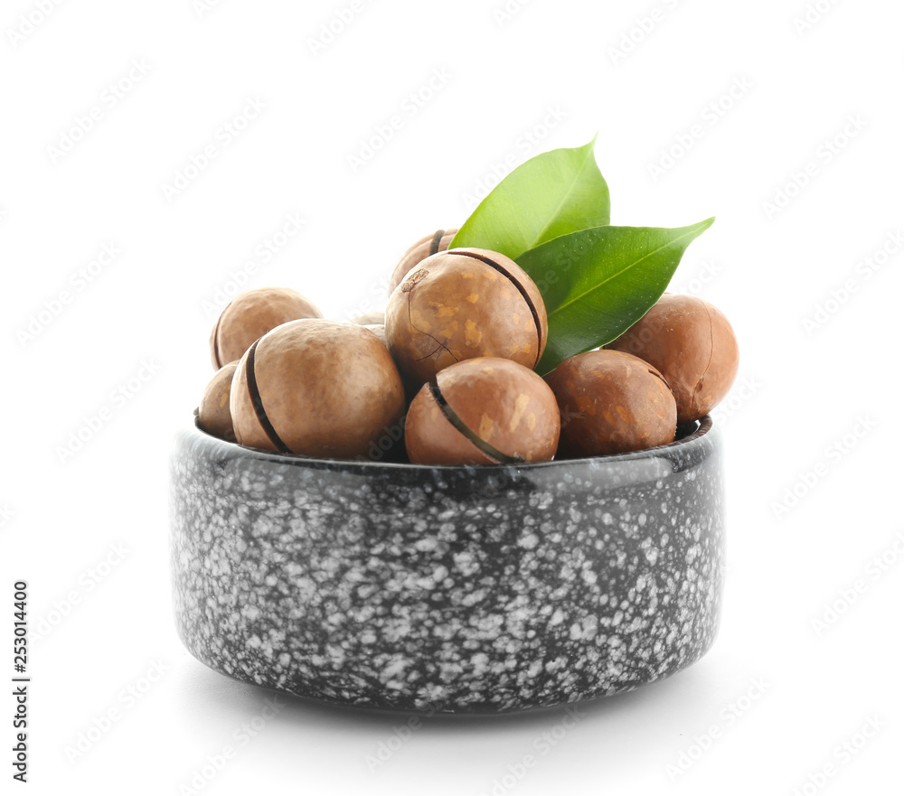 Bowl with macadamia nuts on white background