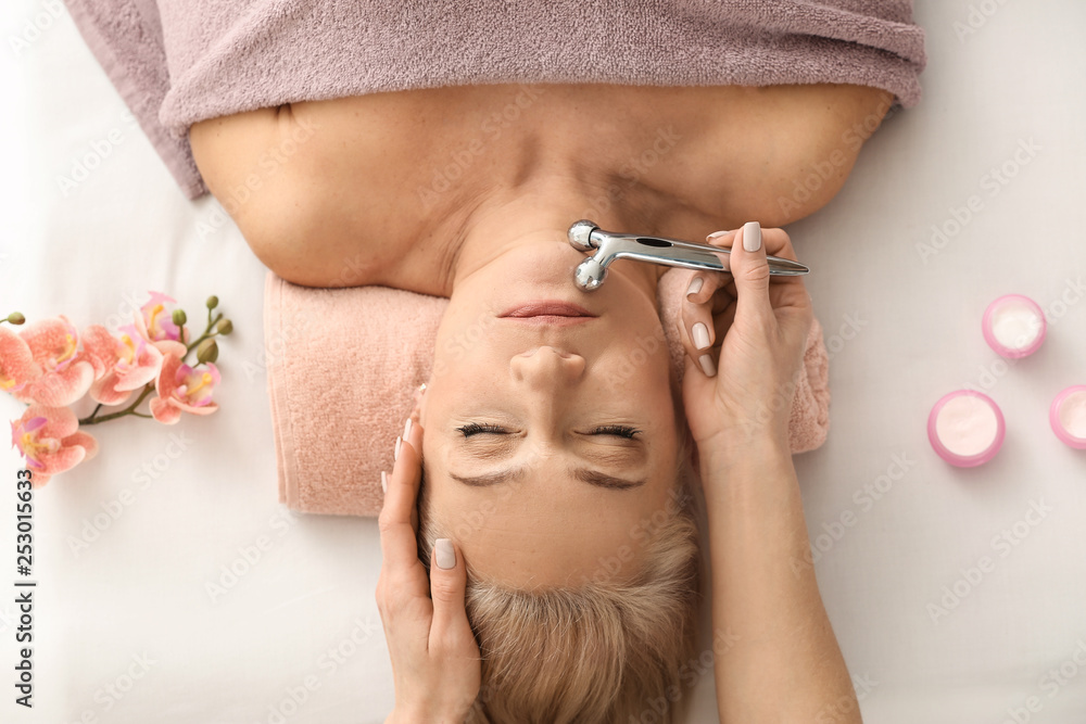 Mature woman receiving face massage in beauty salon