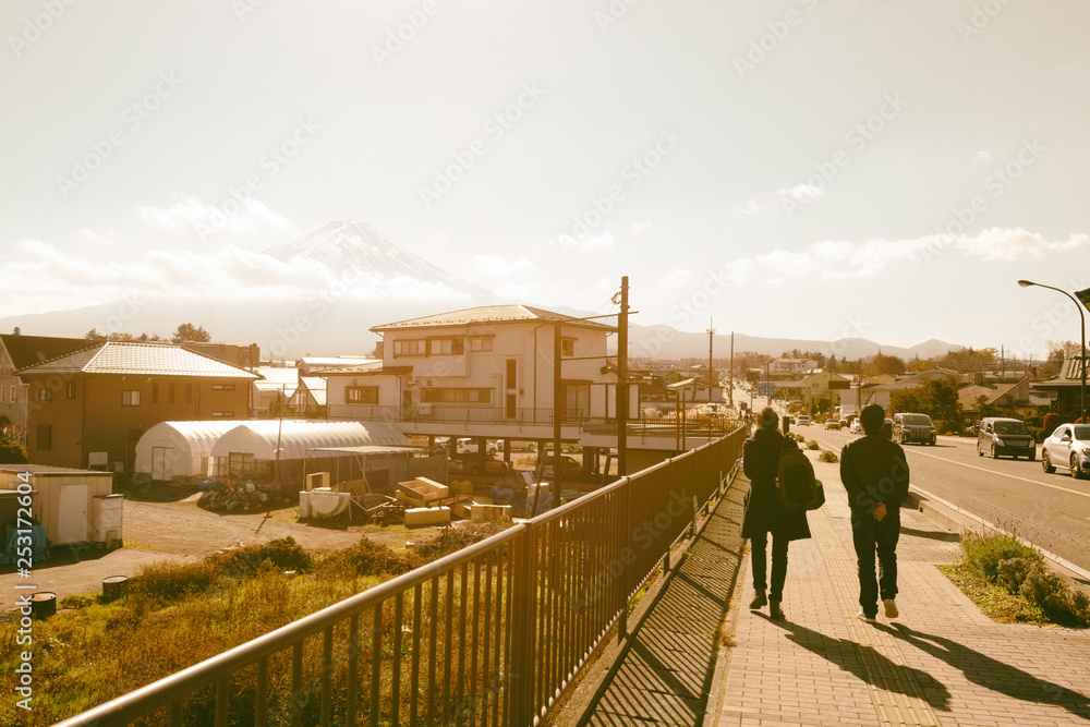 富士山与人们在河谷町的人行道上行走的场景，带有电影色调