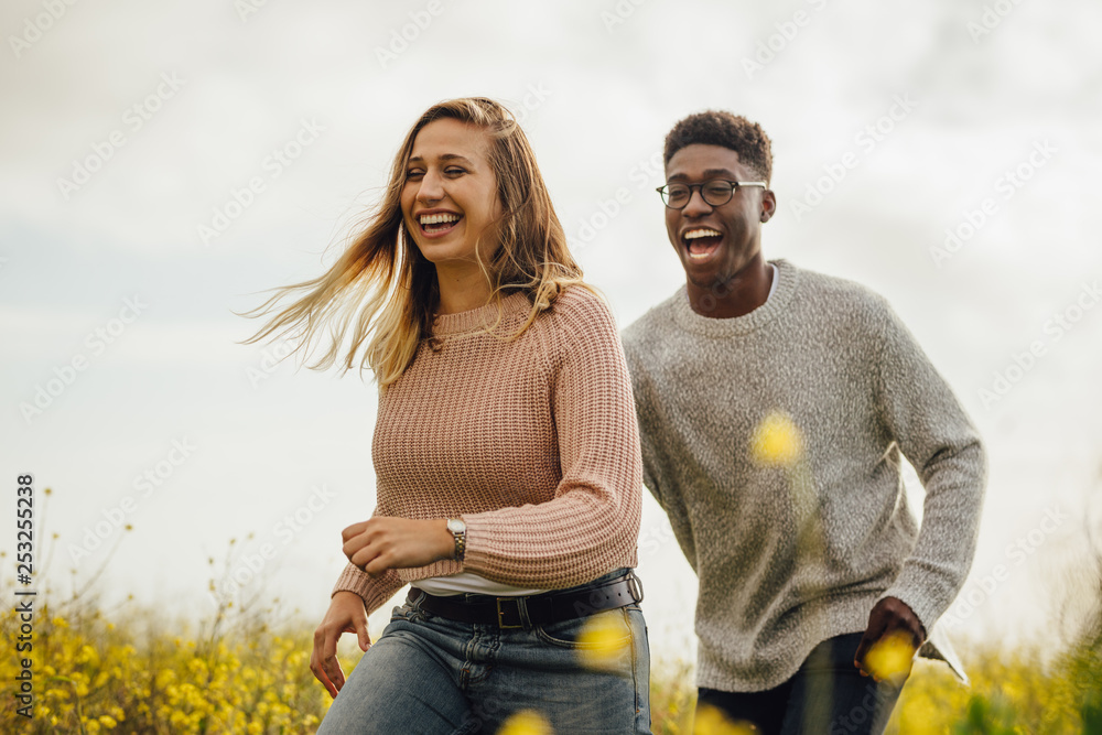 Couple playing and running through a meadow