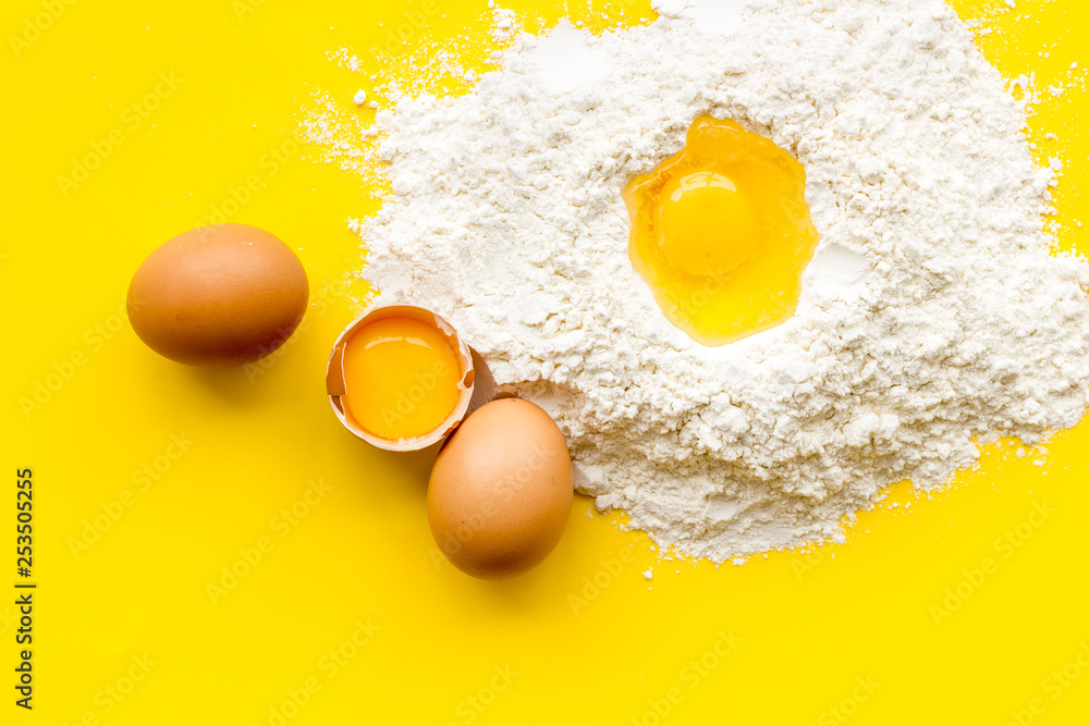 Making dough concept. Pile of flour and eggs on yellow background top view